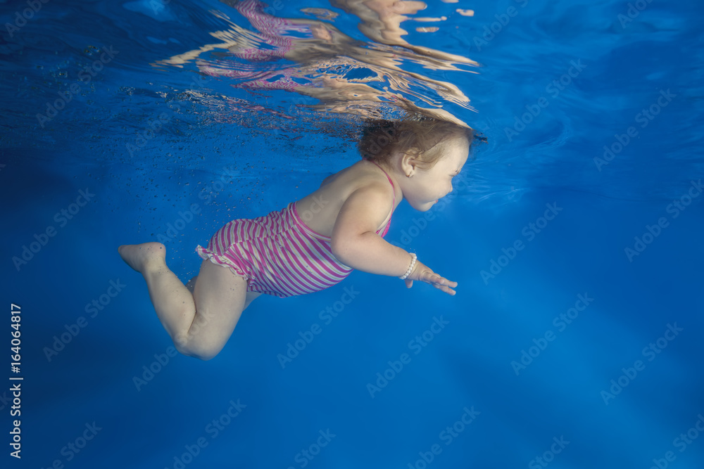 little girl learns to swim underwater in the pool