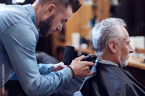 Professional experienced barber working with hair cutting machine