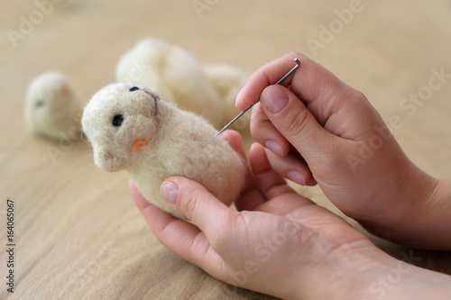 Process of felting a toy from a light wool on a wooden background