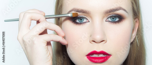 Photography Girl with red lips applying eyeshadows with makeup brush