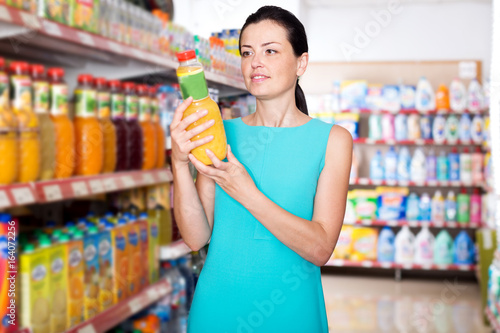 Woman choosing fruit juice on supermarket