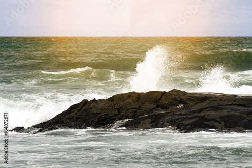 Sea waves break against the rocks at dawn