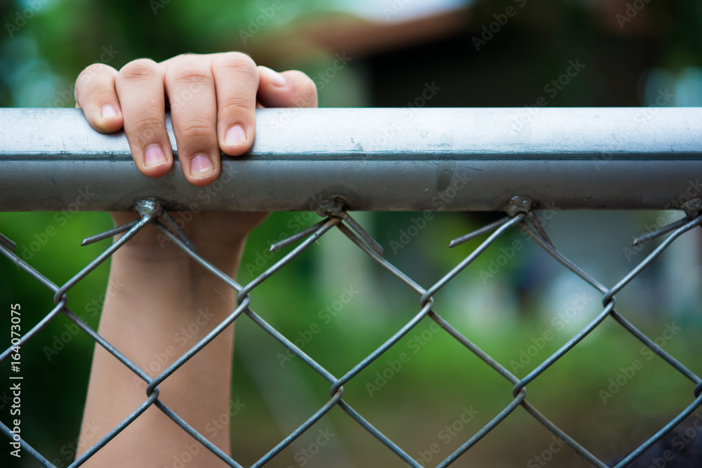Little girl with metal fence, feeling no freedom.