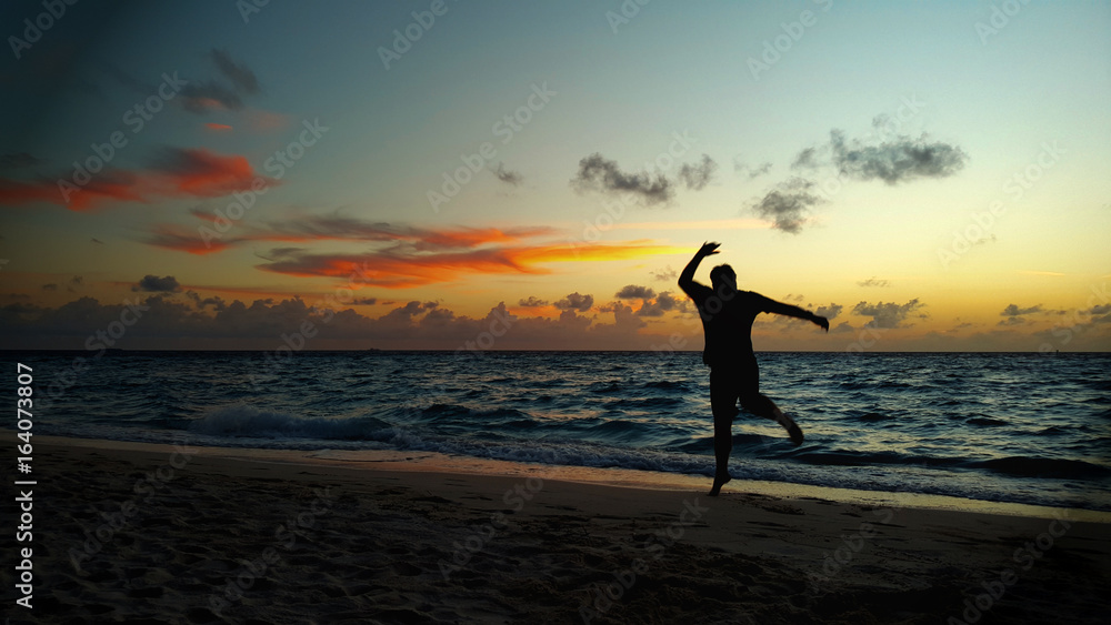 Glücklicher Mann springt am Meer zum Sonnenuntergang