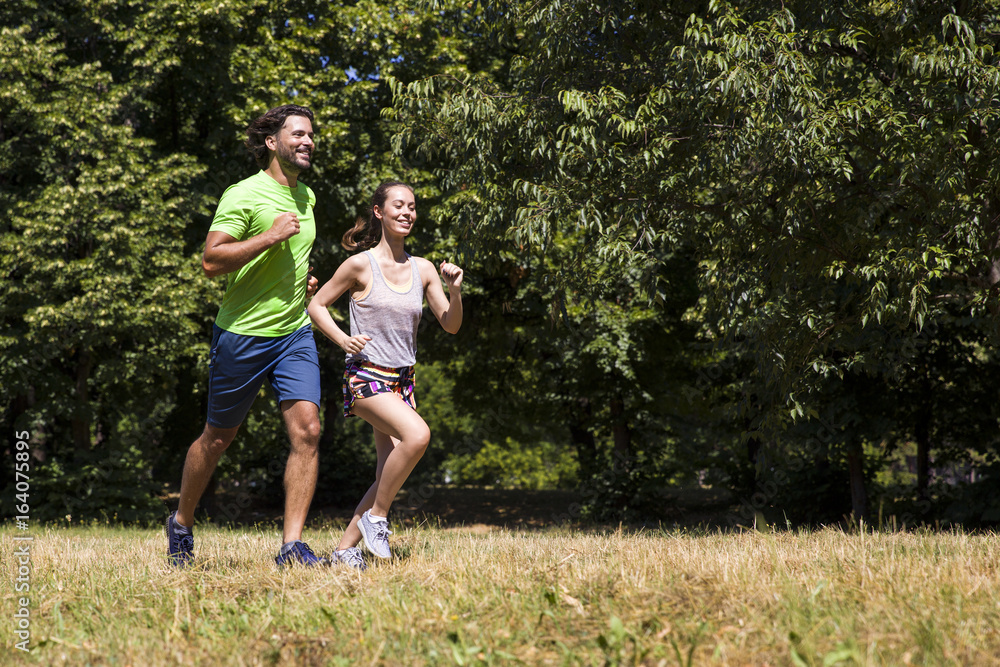 Fototapeta premium Young couple running in the park on a sunny day