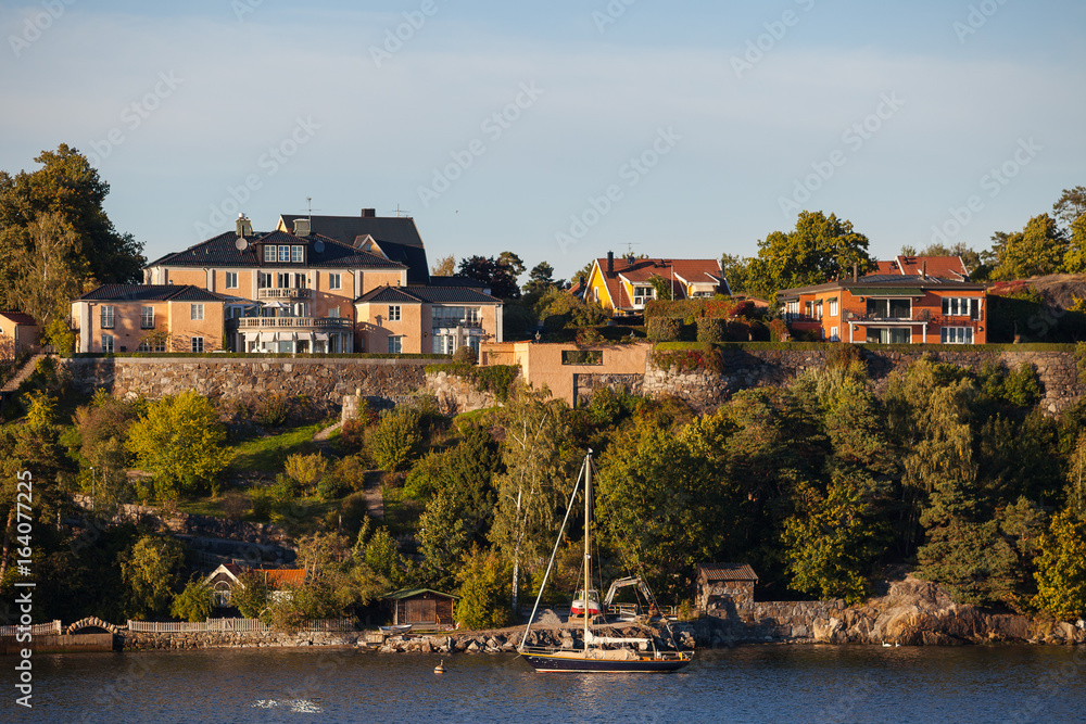View on luxury cottages and private boat along Stockholm archipelago, Sweden. Summer sunset time.
