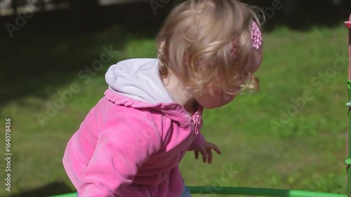 Little two year old blond girl in jeans plays in a children's park, children slide photo