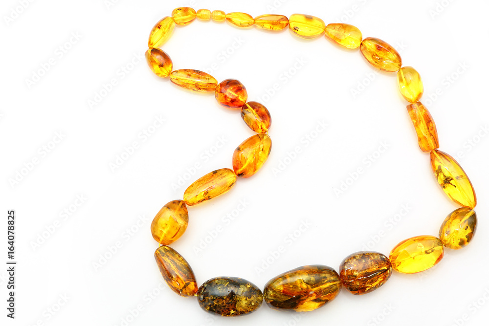 Amber beads made from natural pieces of amber on a white background. Jewelry for women from natural minerals. Petrified resin in the form of beads. Vintage decoration. Top view. Transparent amber Amber beads made from natural pieces of amber on a white background. Jewelry for women from natural minerals. Petrified resin in the form of beads. Vintage decoration. Top view. Transparent amber