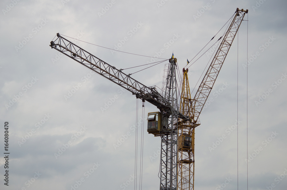 Two construction cranes against a gray rainy sky background Two construction cranes against a gray rainy sky background