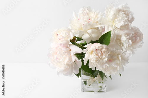 Glass vase with beautiful peonies on white background © Africa Studio