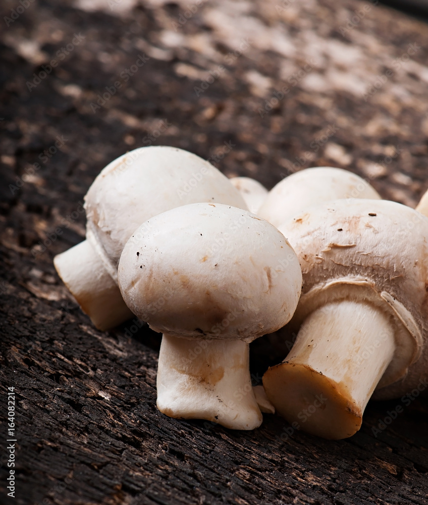 Mushrooms champignons on an old wooden background.