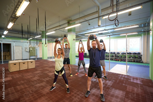 group of people with kettlebells exercising in gym