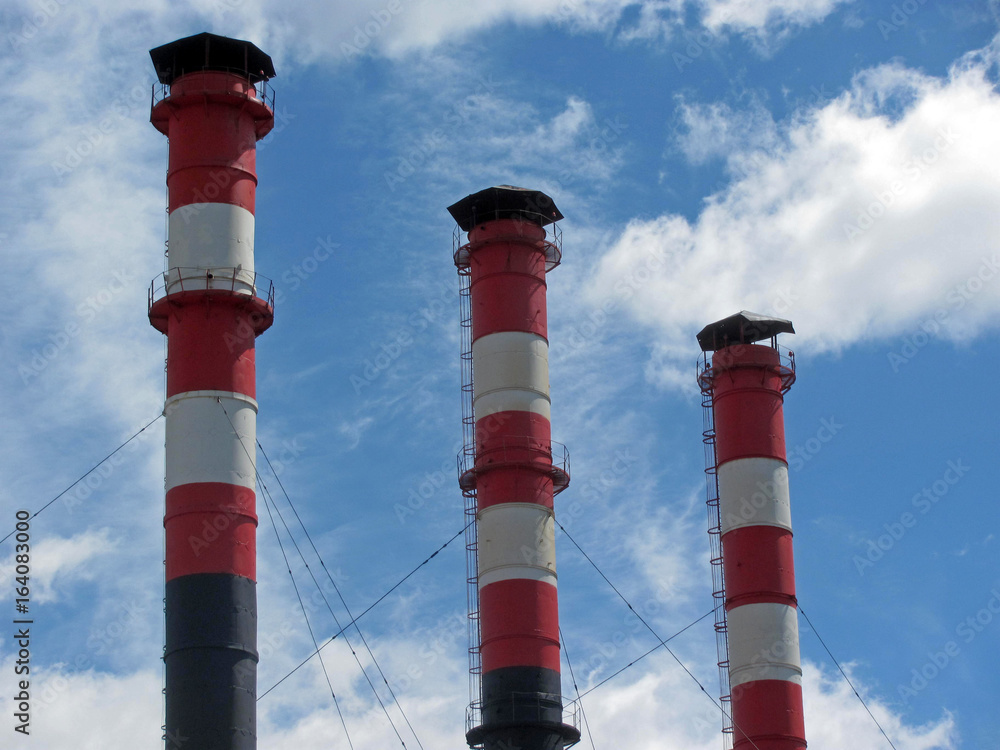 Three striped red and white industrial pipes on background blue sky. Three striped red and white industrial pipes on background blue sky.