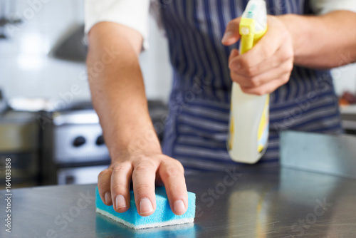 Close Up Of Worker In Restaurant Kitchen Cleaning Down After Service photo