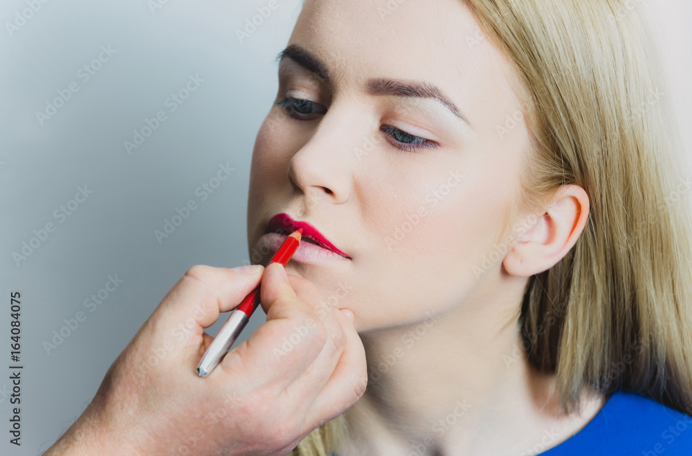 Male hand applying red pencil on woman lips Male hand applying red pencil on woman lips