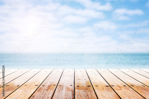 Empty wooden table with party on beach blurred background in summer time.