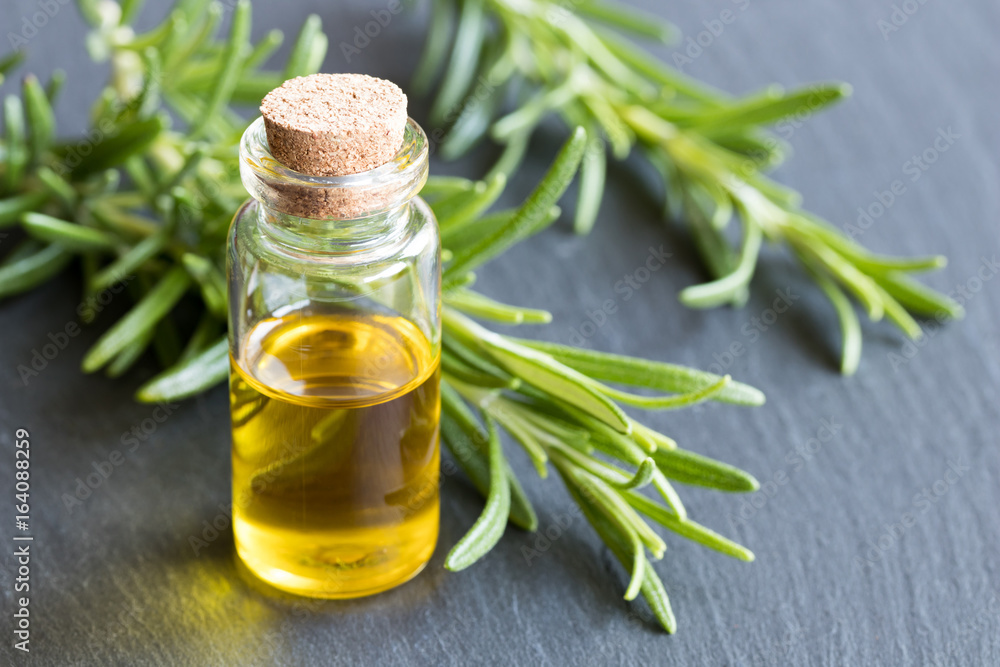 A bottle of essential oil with fresh rosemary twigs A bottle of essential oil with fresh rosemary twigs
