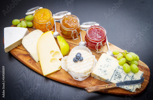 Foto wooden cutting board with cheese and jams