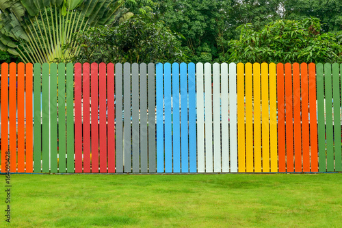 colorful fence with lawns and tree in backyard.