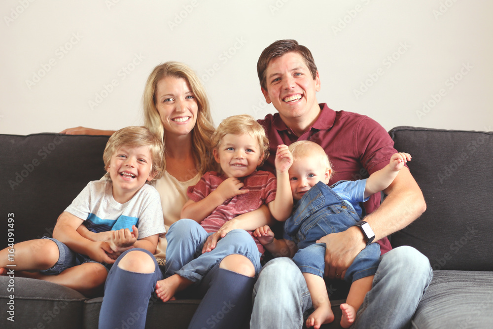 Young family with three boys lifestyle at home on the couch playing together