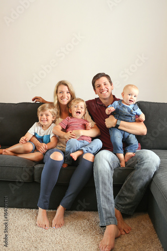 Young family with three boys lifestyle at home on the couch playing together