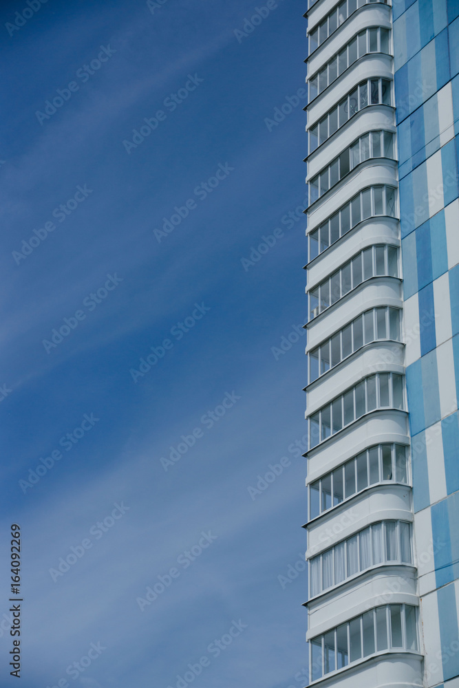 New blue multi-storey house on a background of blue sky. Modern buildings New blue multi-storey house on a background of blue sky. Modern buildings