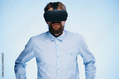 A young guy with a beard on a blue background with virtual reality glasses © SHOTPRIME STUDIO