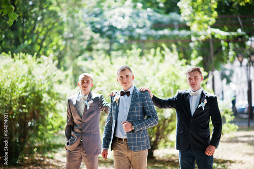 Handsome groom with his groomsmen walking in the park next to the lake.