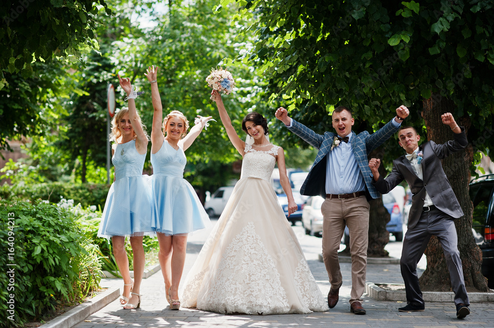 Attractive wedding couple and bridesmaids with groomsmen are having fun outdoors.