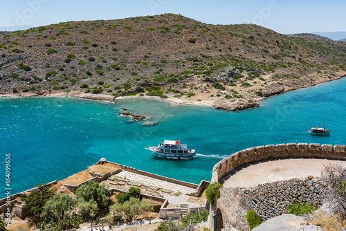 Top of Spinalonga island. View to blue aegian sea with boats and Kalydon island.