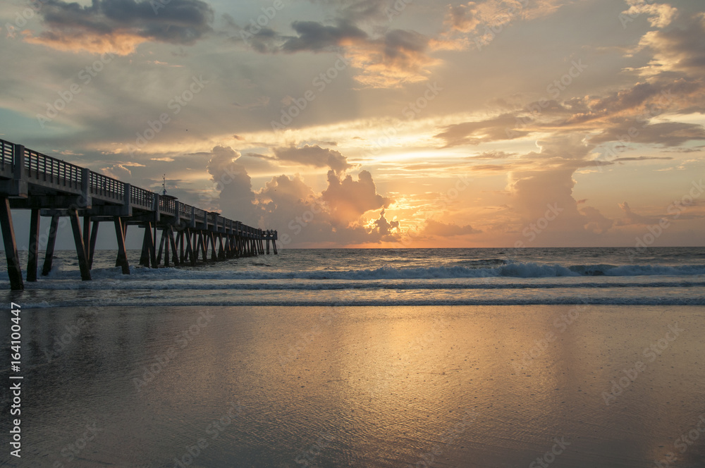 Sunrise over the atlantic ocean with beach and pier