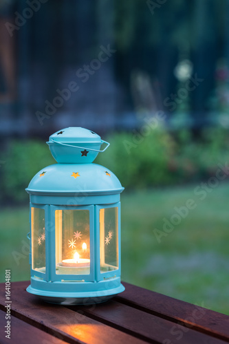 Scented candle in a pretty lantern with outdoor green background