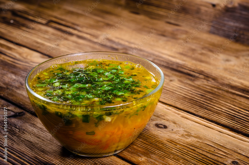 Vegetable soup in a glass bowl on wooden table Vegetable soup in a glass bowl on wooden table