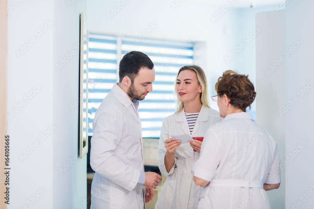 Mature doctor discussing with nurses in a hallway hospital. Doctor discussing patient case status with his medical staff after operation. Mature doctor discussing with nurses in a hallway hospital. Doctor discussing patient case status with his medical staff after operation.