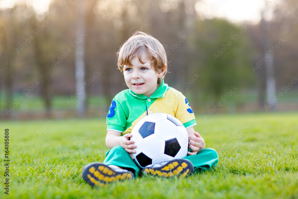 Little cute kid boy of 4 playing soccer with football on field, outdoors Little cute kid boy of 4 playing soccer with football on field, outdoors