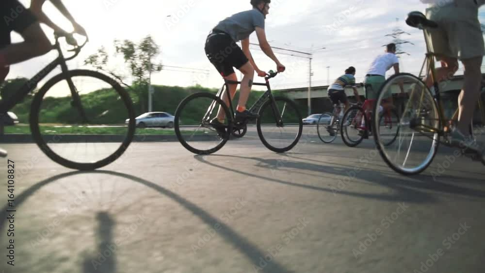 Group of cyclists riding fixed gear bikes on the road, steadycome shot, slow motion Group of cyclists riding fixed gear bikes on the road, steadycome shot, slow motion