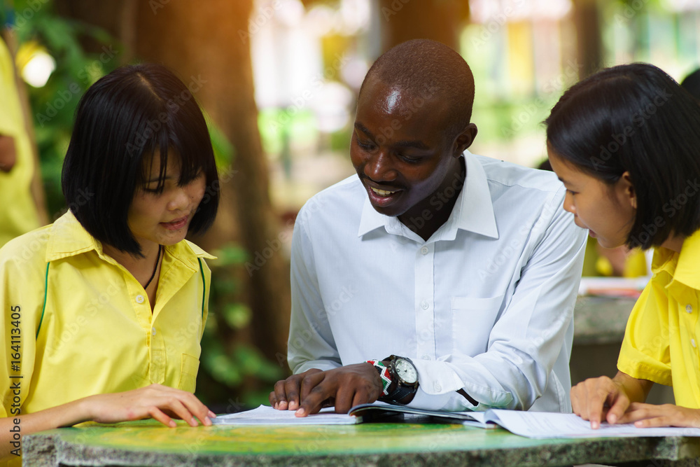 American teacher teaching asian student about foreign languages. American teacher teaching asian student about foreign languages.