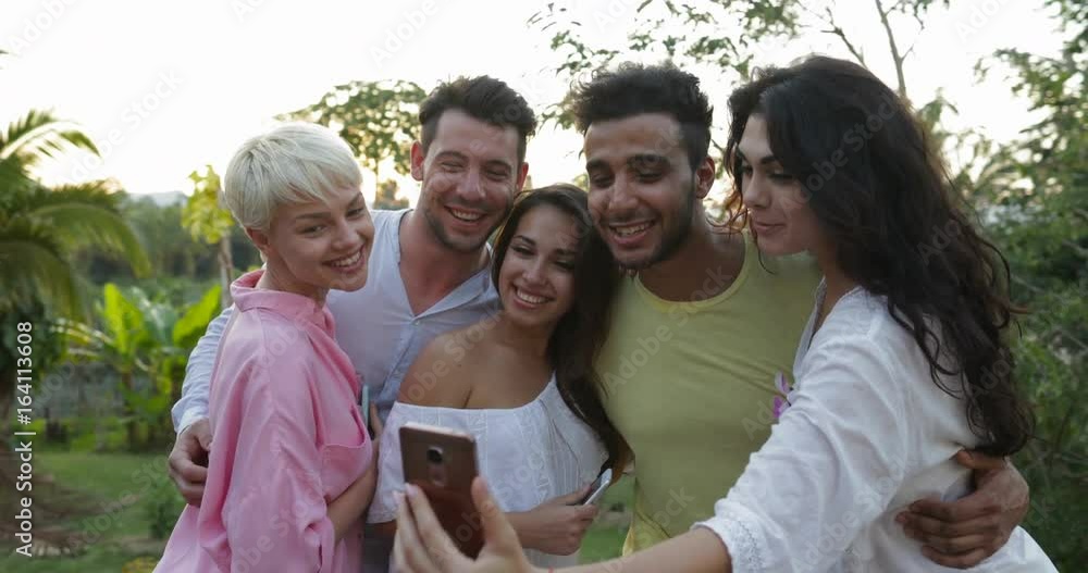 Group Of Friends Taking Selfie Photo On Cell Smart Phone On Summer Terrace Over Sunset Landscape, Friends Posing For Self Portrait Outdoors Slow Motion 60 Group Of Friends Taking Selfie Photo On Cell Smart Phone On Summer Terrace Over Sunset Landscape, Friends Posing For Self Portrait Outdoors Slow Motion 60