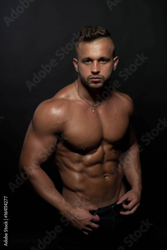 Handsome, strong and sexy male fitness model / MMA fighter poses on dark background	