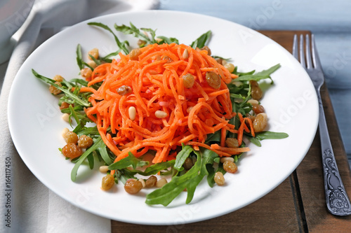 Delicious carrot raisin salad with greens on wooden board