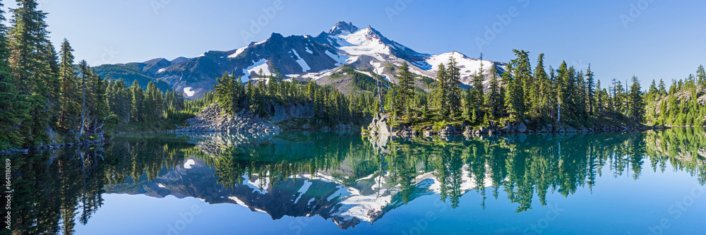 Volcanic mountain in morning light reflected in calm waters of lake.