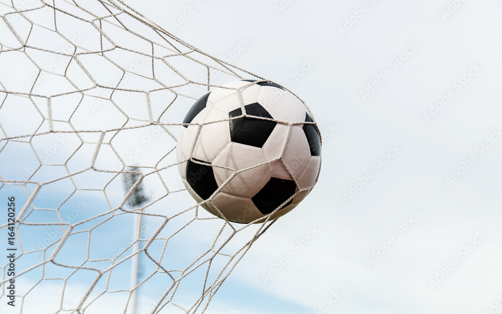 Fototapeta premium Soccer football in Goal net with the sky field.