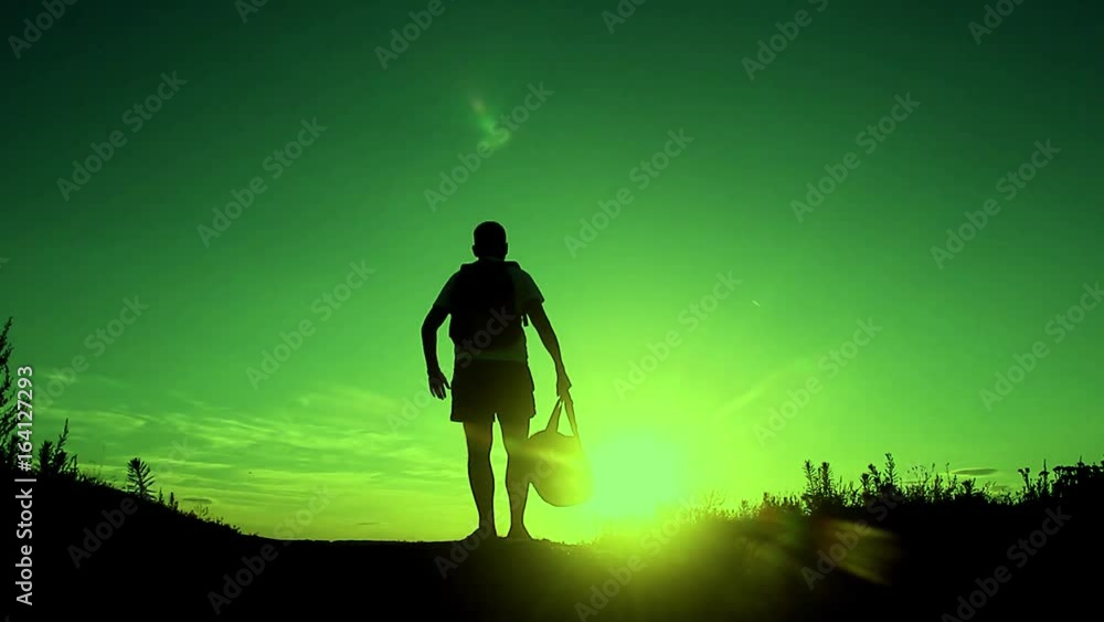 Silhouette of the people with a shoulder bag to see the sun Sky background. Man standing on the mountain with his arms wide open. Silhouette of the people with a shoulder bag to see the sun Sky background. Man standing on the mountain with his arms wide open.
