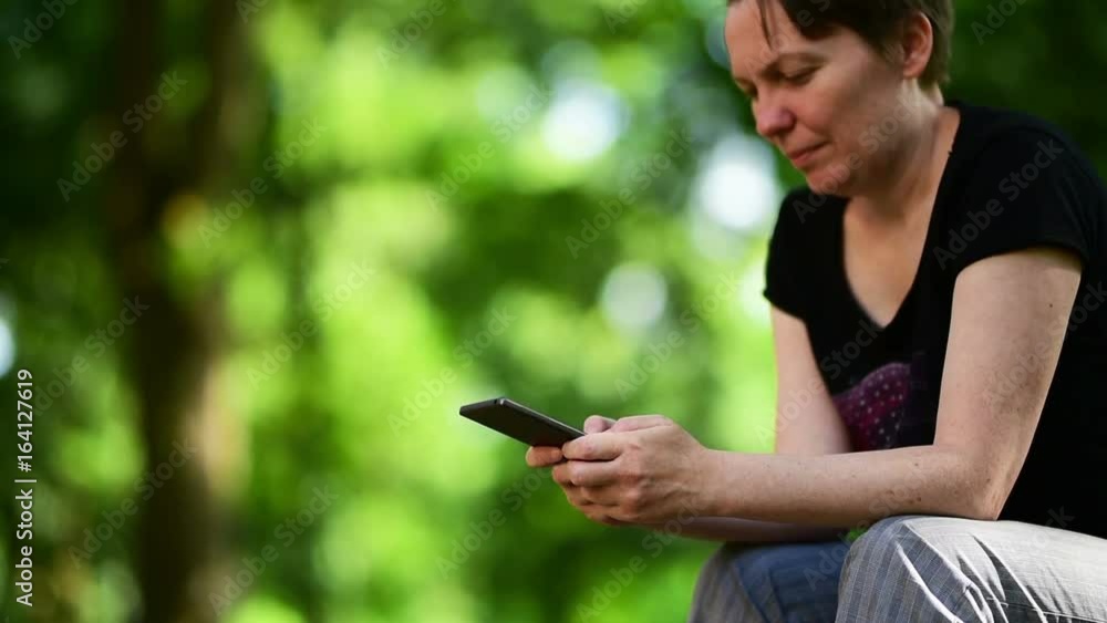 Woman using smartphone in public park, female hands typing sms text message or using mobile app on public wi-fi network Woman using smartphone in public park, female hands typing sms text message or using mobile app on public wi-fi network