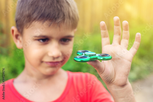 A boy plays with spinner twisting it in his hand on outdoors. Trends in children's anti-stress toys