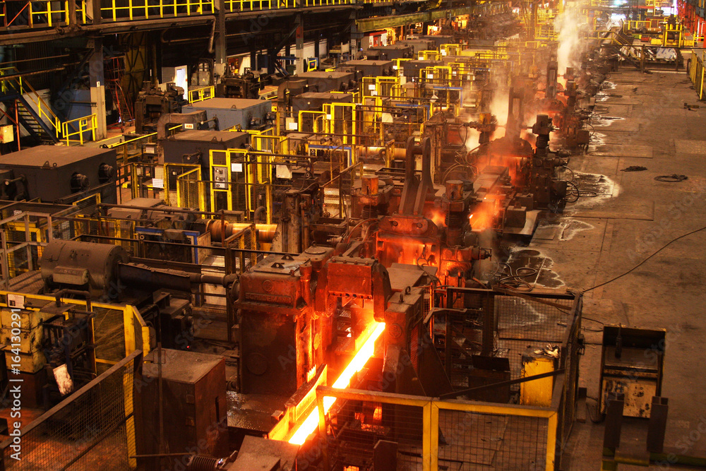 Red hot steel bar in multi stand rolling mill. Stock Photo Adobe Stock