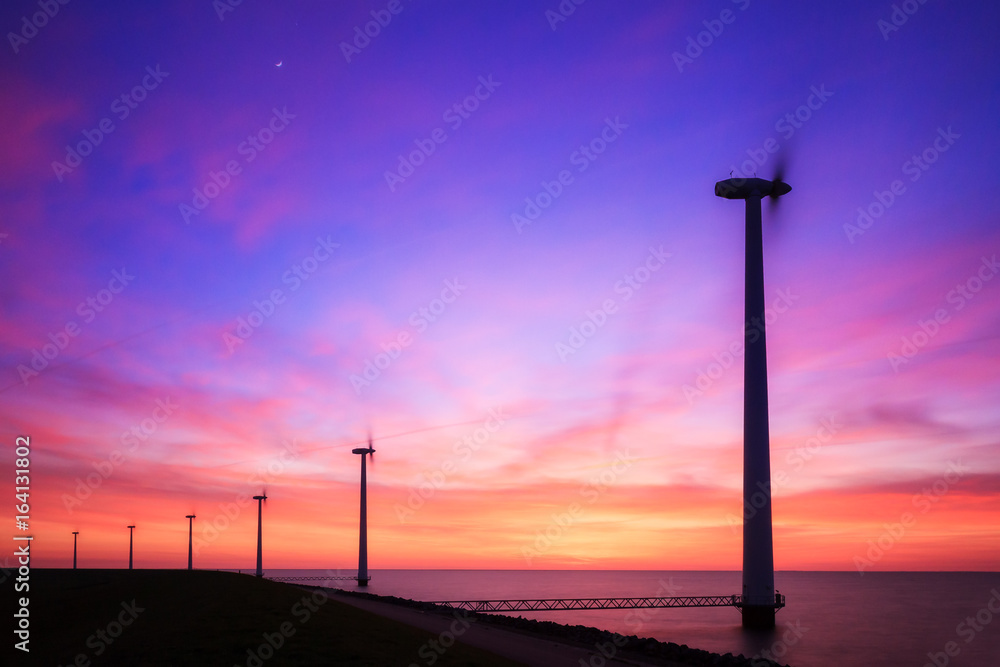 Beautiful sunset at the dike with wind turbines at the Markermeer in the Netherlands 