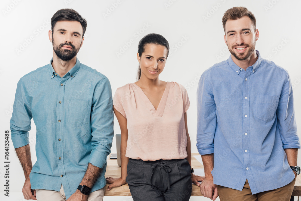 portrait of businessmen and smiling businesswoman standing at workplace in office portrait of businessmen and smiling businesswoman standing at workplace in office