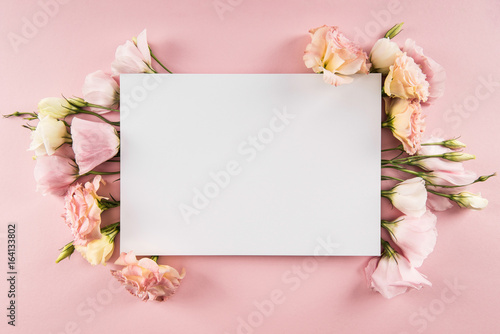 Top view of beautiful blooming flowers and blank card isolated on pink © LIGHTFIELD STUDIOS
