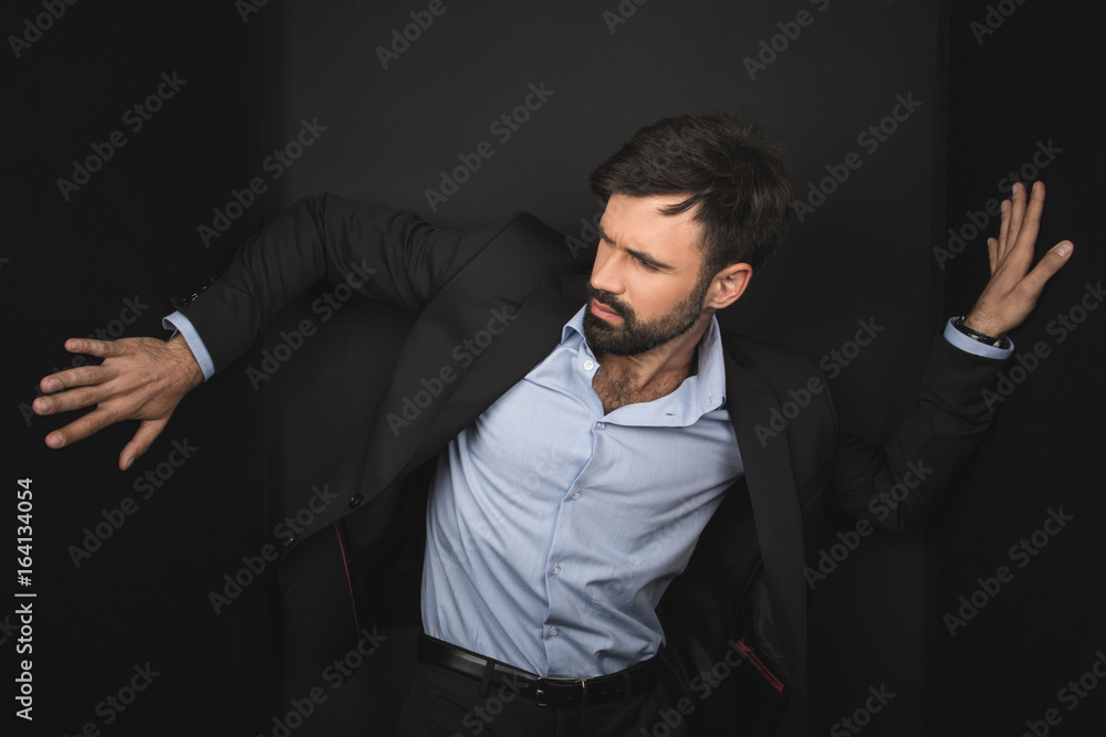 handsome bearded businessman posing in black suit, isolated on black